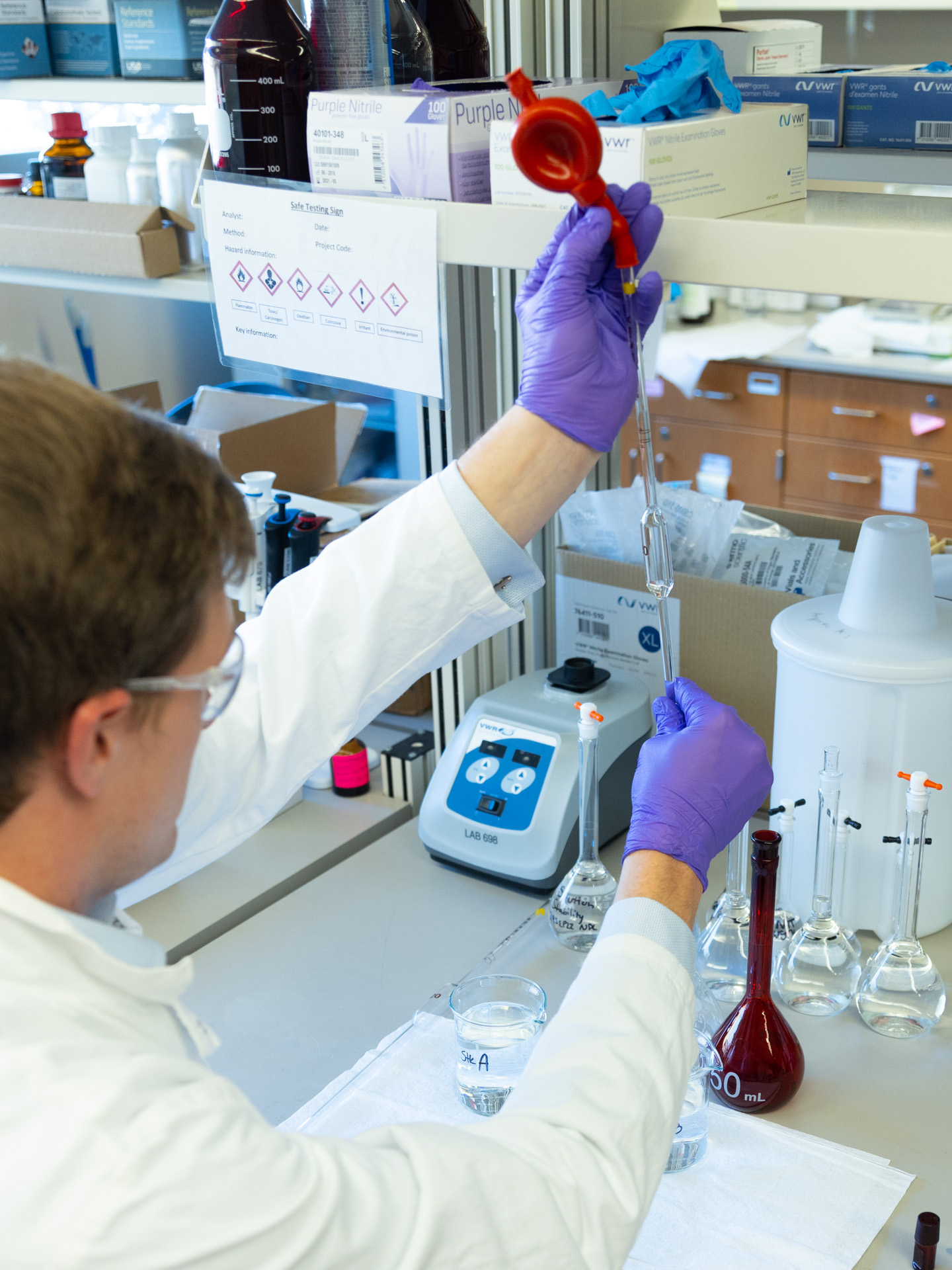 KU Innovation Center-Site Photos-5311 A man in a labcoat and other personal with protective equipment holds a long pipette in a lab at the Bioscience and Technology Business Incubator in Lawrence, KS.