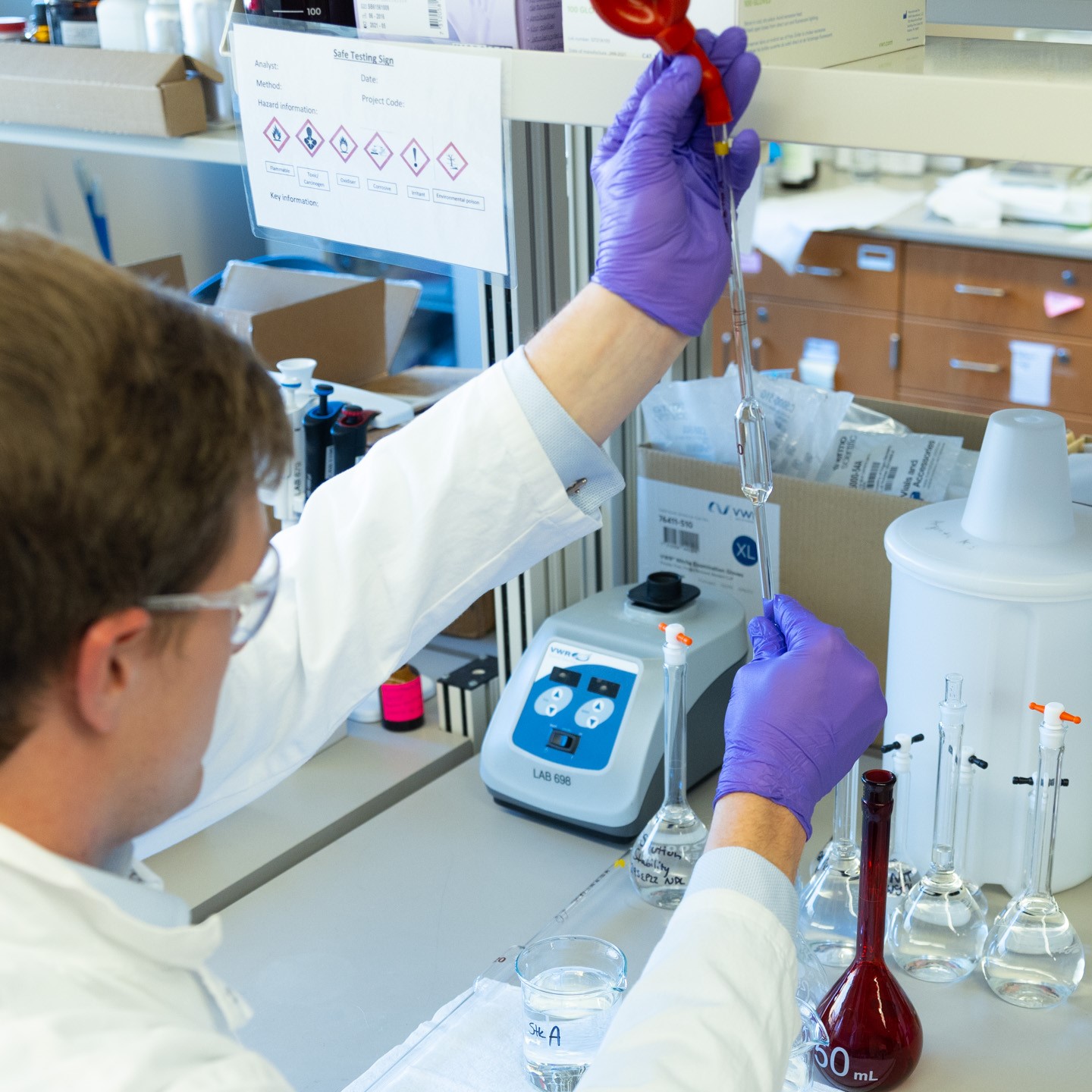 KU-Innovation-Center-Site-Photos-5311-sq A man in a labcoat and other personal with protective equipment holds a long pipette in a lab at the Bioscience and Technology Business Incubator in Lawrence, KS.